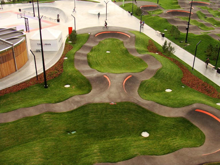 Aerial view of a skatepark with Velosolutions pump track, featuring smooth curves and lush lawns.