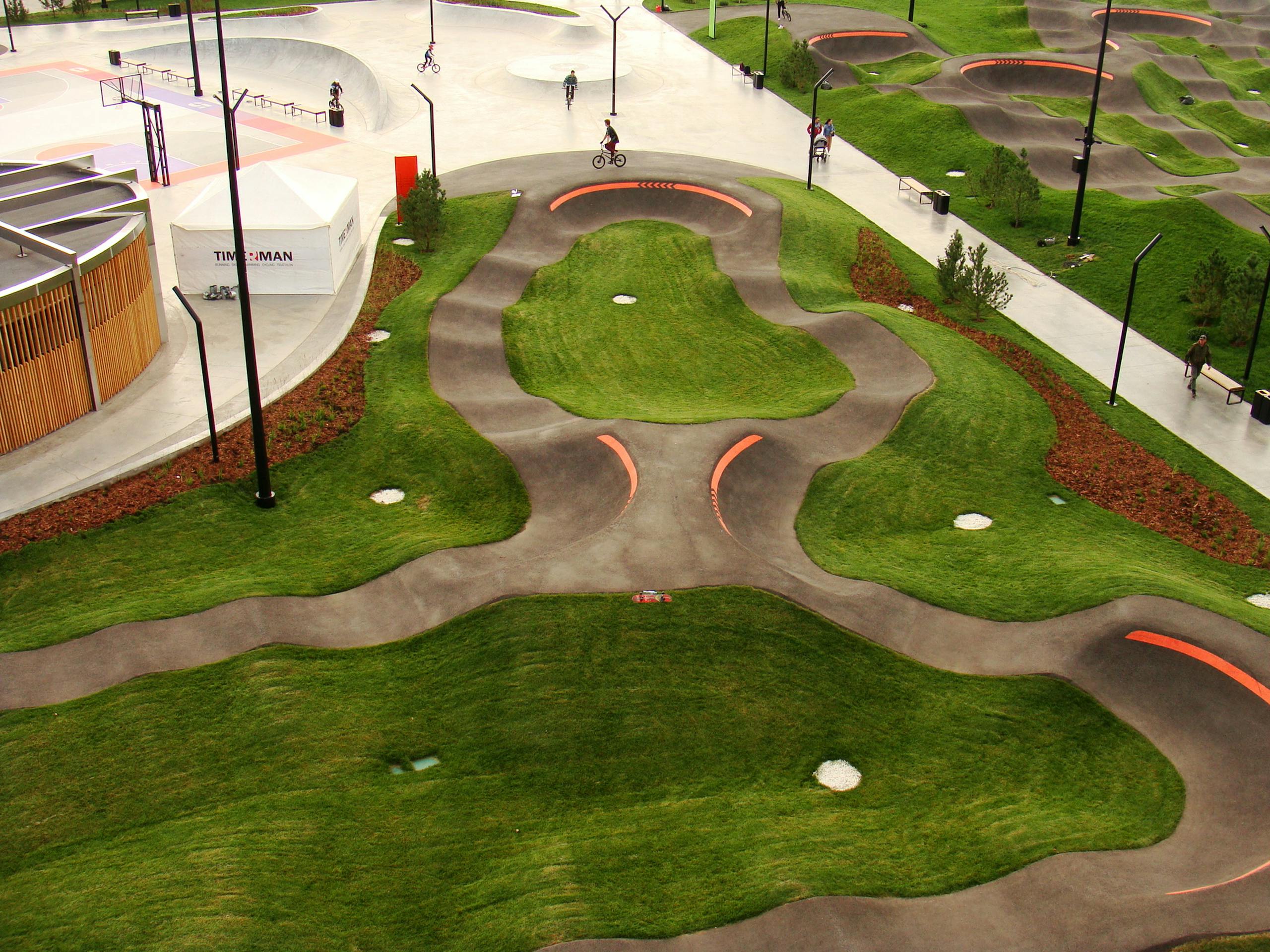 Aerial view of a skatepark with Velosolutions pump track, featuring smooth curves and lush lawns.