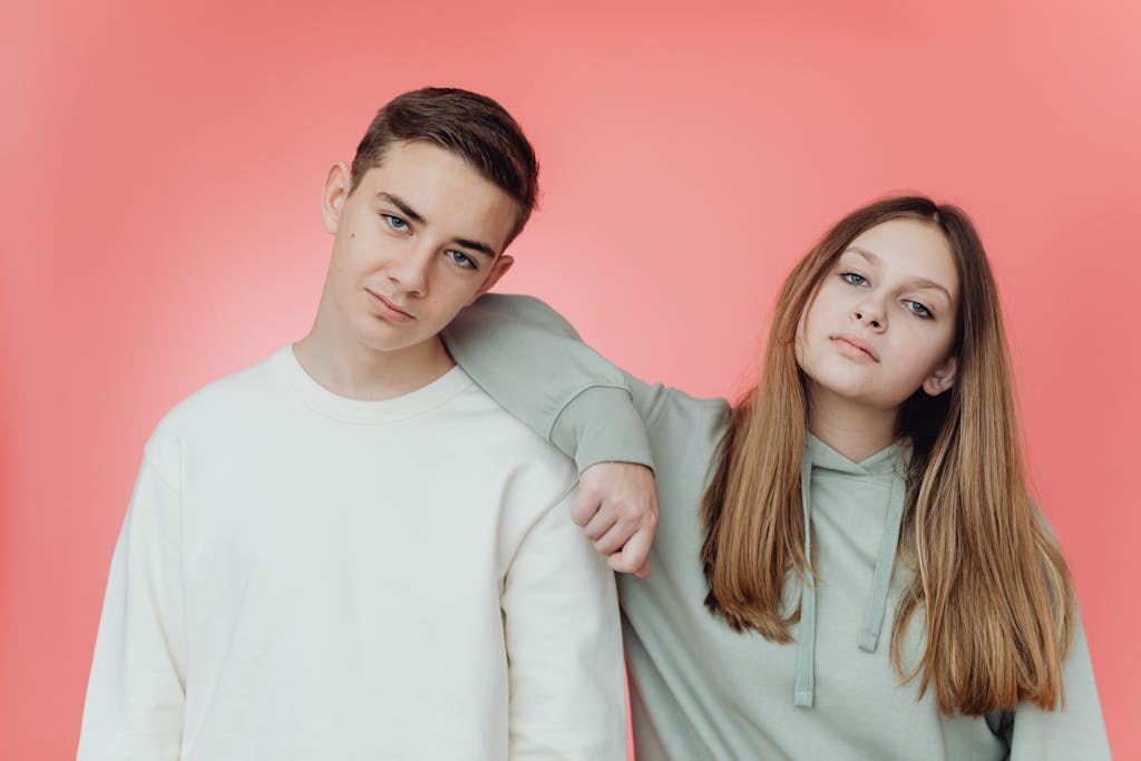 Portrait of stylish teenagers against a pink studio backdrop.