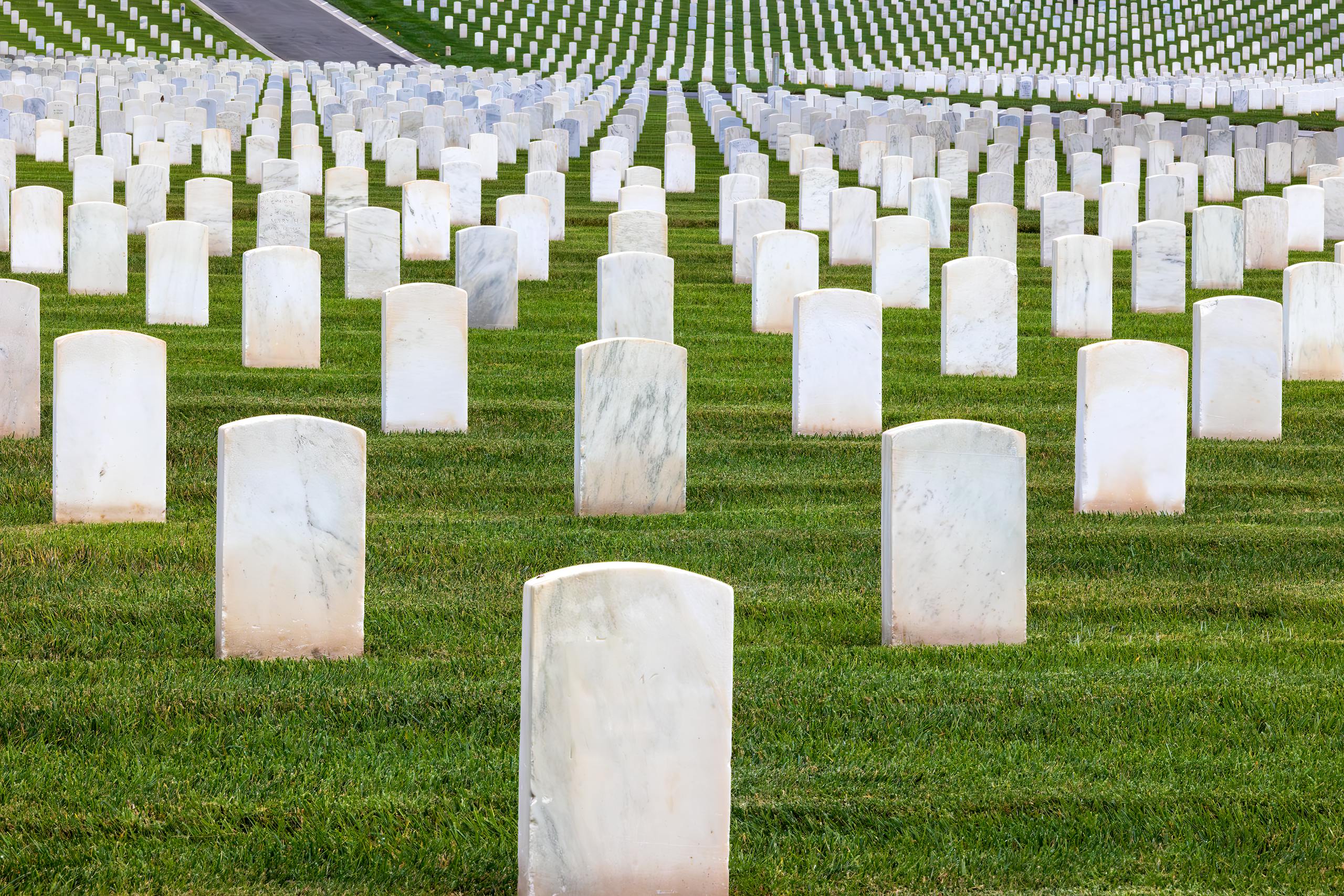 Quiet moment captured at a military cemetery with aligned white tombstones on green grass.