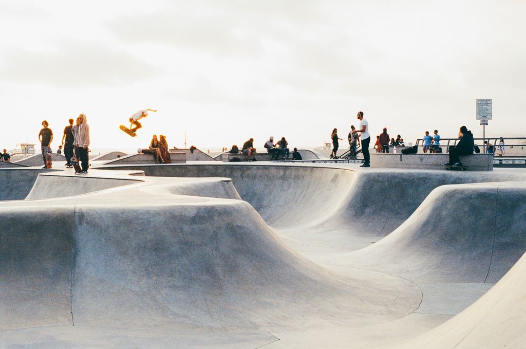 A vibrant scene of skateboarders performing tricks at a lively outdoor skatepark.